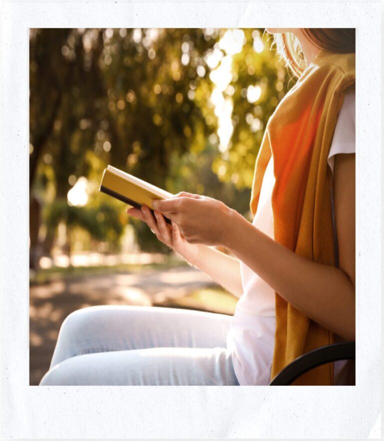 Girl reading a short powerful devotion book outside on a sunny day