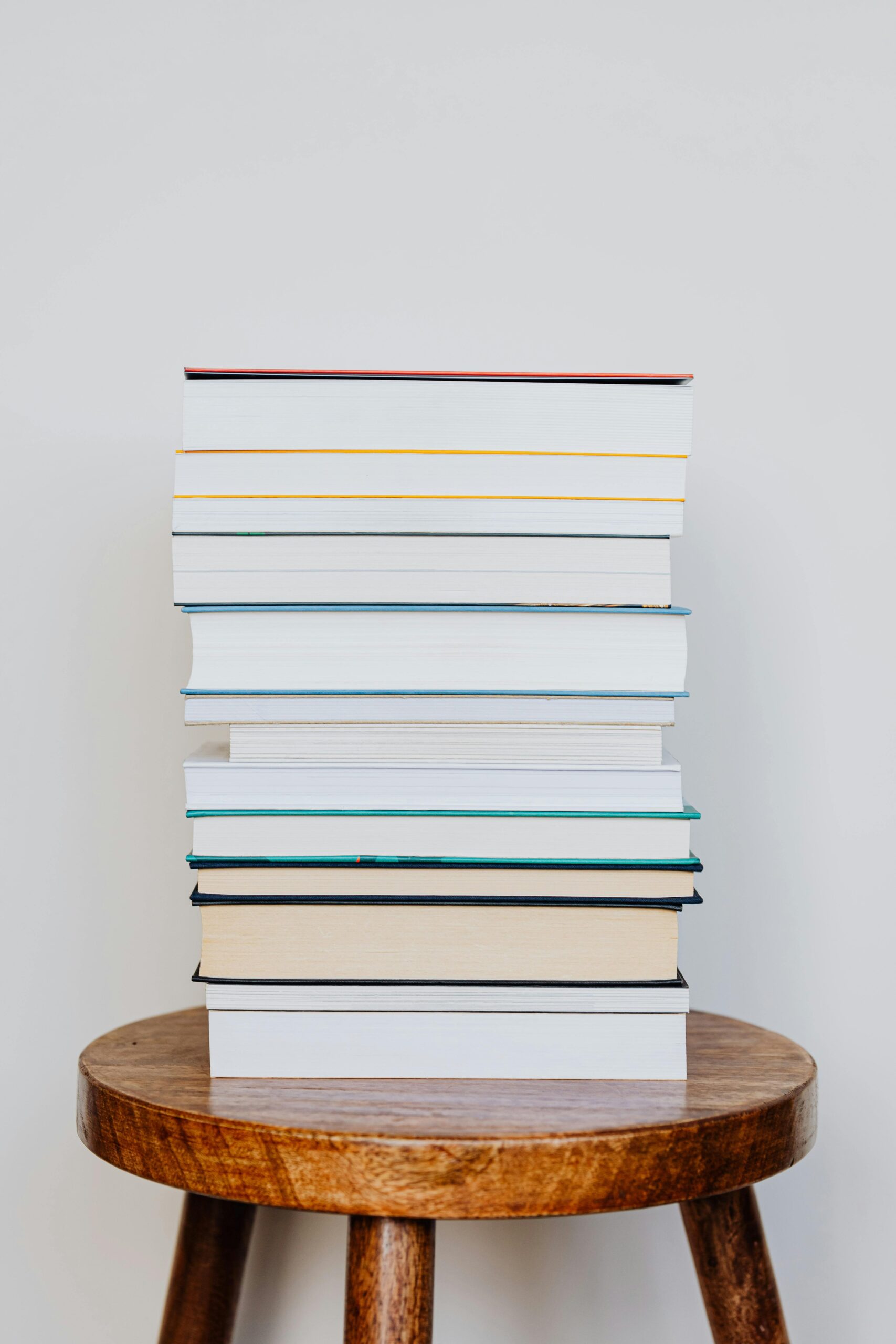 A neat stack of books placed on a rustic wooden stool, perfect for reading scenes.